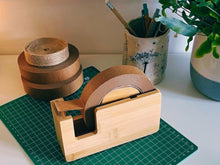 Load image into Gallery viewer, Wooden tape dispenser on a green cutting mat with &#39;Eco Tape&#39; text, surrounded by office supplies.
