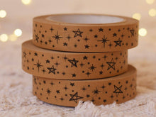 Load image into Gallery viewer, Three rolls of brown tape with star patterns stacked on a textured surface with blurred lights in the background.
